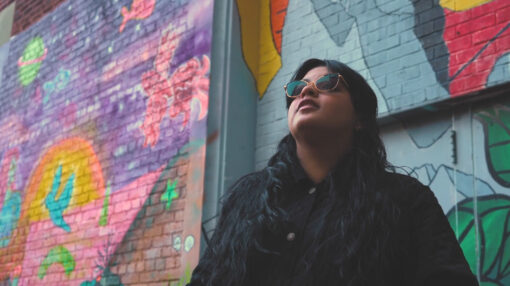 Student attending a transfer school standing in front of a mural looking up