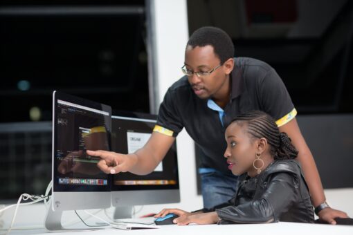 Male teacher of color teaching a student of color in a computer lab
