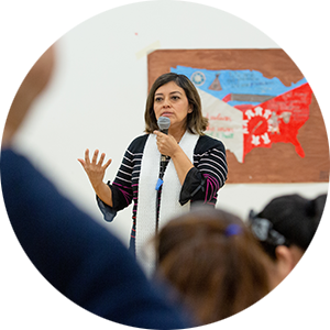 Educator at the front of a crowded room with a microphone