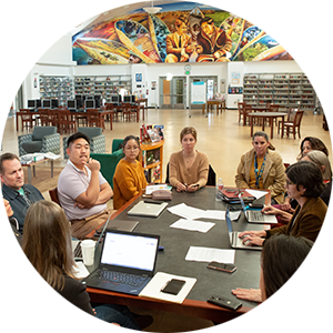 Group of educators sitting around a conference table in a colorful school building