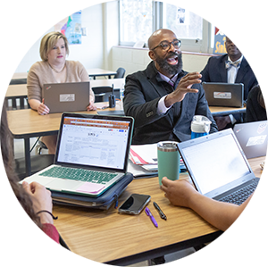 Educators at a table with computers having a discussion